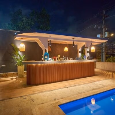 Bar junto a la piscina de Alacarta VIP Medellín con iluminación cálida y cócteles premium.
