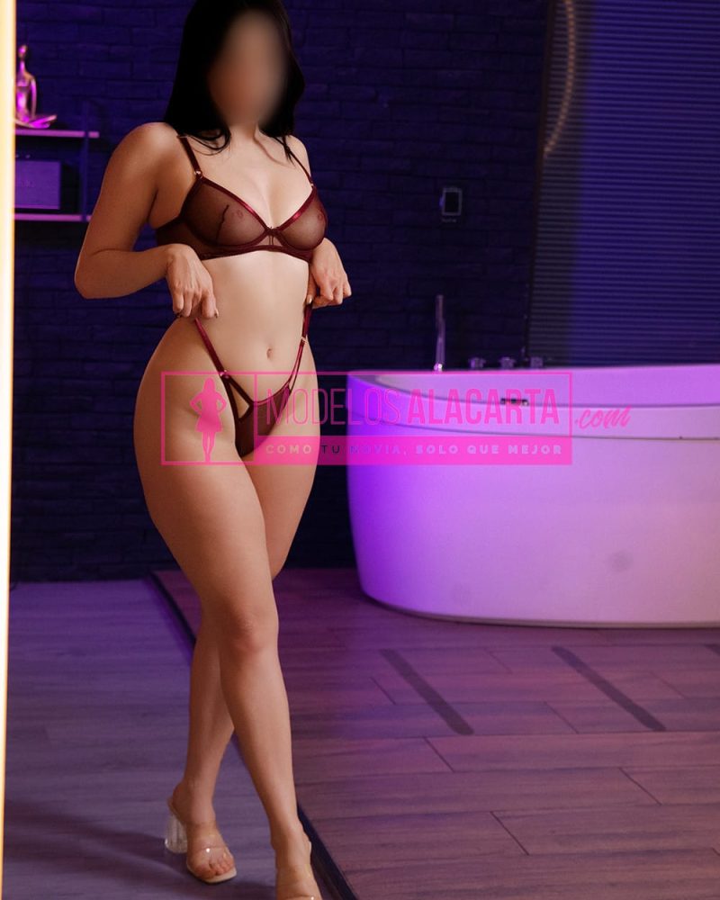 Escort natural en el poblado Camila Rojo posando de pie con lencería oscura junto a una tina