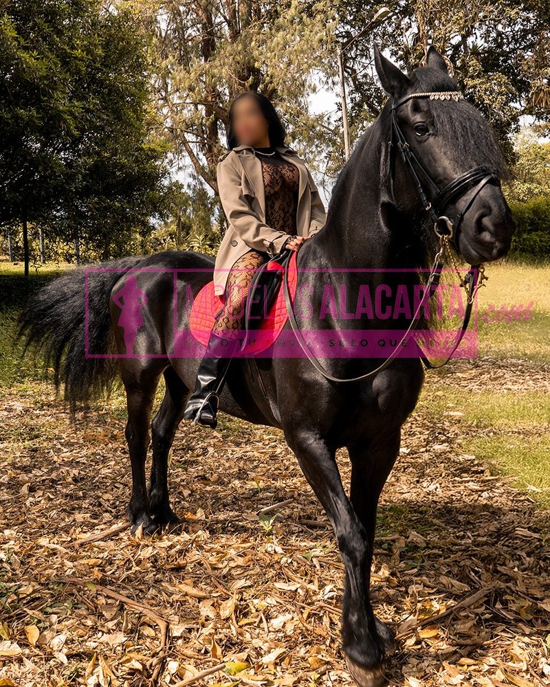 Mujer madura rica en Medellín, Naty Gold, montando un caballo con gracia y estilo, transmitiendo una sensación de poder y elegancia
